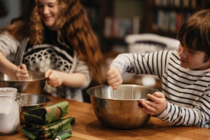 Younger boy and girl baking together in the kitchen. As your kids age, parenting changes. Learn how to walk through this with a parent coach in Southlake, TX. You can meet us in person or via online therapy today. Begin parenting coaching in Texas soon!