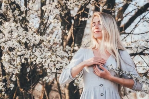 Woman breathing underneath a flower tree. Calming yourself when experiencing anxiety does not have to be difficult. Learning breathing techniques leaves you feeling more empowered than ever to tackle your anxiety.
